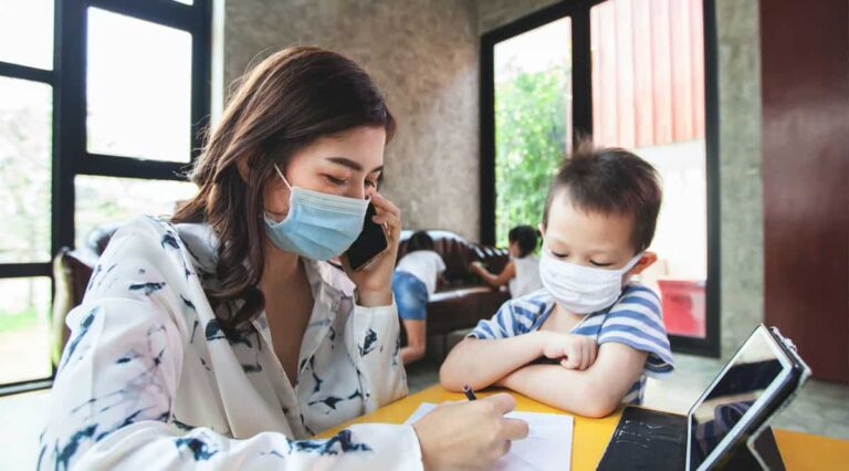 疫情期間一對戴著口罩的母子坐在桌子前